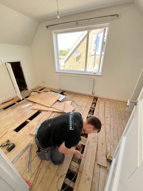 New electrical cables being installed beneath lifted floorboards during a full house rewire in Westdene, Brighton